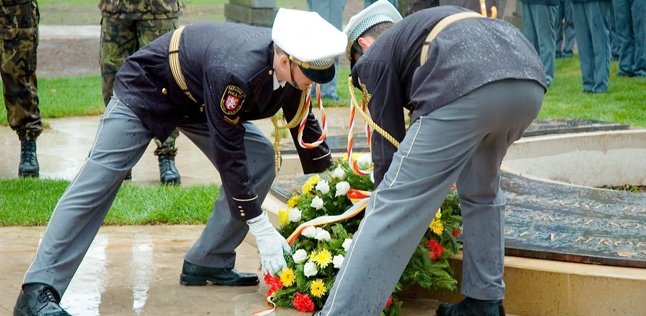 Dva vojáci kladou pamětní věnec k hrobu.